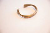 Side profile of the antique bronze cuff, showing its open shape and aged patina.