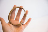 The solid, curved form of the antique bronze snake cuff shown in hand for scale.