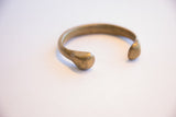 Detail of the antique bronze snake cuff's rounded terminal and time-softened patina.