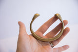 Antique African bronze snake cuff held in hand to show its solid form and scale.