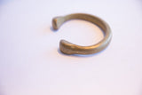 The thick, open design and aged patina of the antique bronze cuff bracelet.