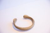 The open, rounded ends of the heavy antique African bronze snake cuff.