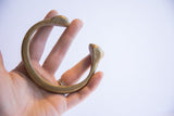 Antique bronze snake cuff held in hand, showing its wearable scale and aged patina.