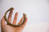 Antique bronze snake cuff bracelet held to display its sculptural form and scale.