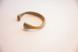 Angled view of the antique African cuff showing its solid, curved form and flared terminal.