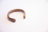 The open C-shape of the antique African cuff showing its warm, aged patina.