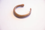 Aged bronze patina and handcrafted texture of an antique African cuff bracelet.