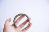 Antique snake cuff bracelet held in hand, highlighting its curved form and patina.