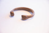 The open design of an antique African snake cuff with a time-softened bronze patina.