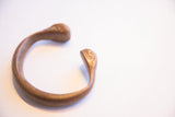 Antique African snake cuff bracelet showing its open form and time-softened bronze finish.