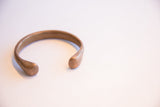 Open-ended antique African cuff bracelet showing its smooth, curved form and bronze patina.