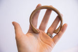 Antique African snake cuff bracelet held in a palm to demonstrate its size and form.