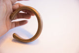 The substantial C-shaped form and aged bronze finish of an antique African cuff.