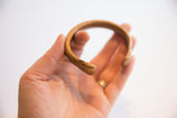 Angled view of the handmade African snake cuff showing its curved form and etched details.