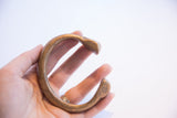 Hand holding an antique snake cuff bracelet to show its C-shape and scale.