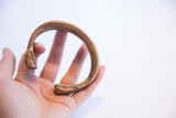 Antique African snake cuff bracelet held in hand, showing its scale and time-softened patina.