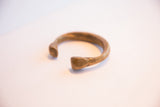 Small circular markings and aged patina on the handcrafted brass snake cuff terminal.