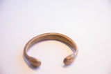 The hand-formed curve and aged brass patina of the antique African snake cuff bracelet.