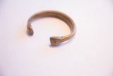 Warm, aged patina on the hand-forged opening of an antique snake cuff.