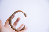 Antique snake cuff bracelet held in hand, showing its substantial form and patina.