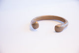 Smooth, rounded terminals of the handmade African snake cuff with an aged patina.