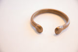 Open form and aged patina of an antique snake cuff bracelet.