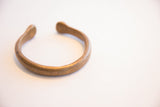 The open curve and smooth, time-softened metal of an antique African cuff.
