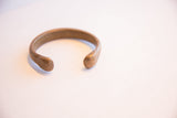 Aged patina on the smooth, rounded ends of an antique snake cuff.