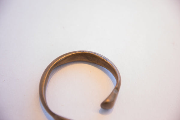 The open end and curved form of a handmade antique snake cuff bracelet.