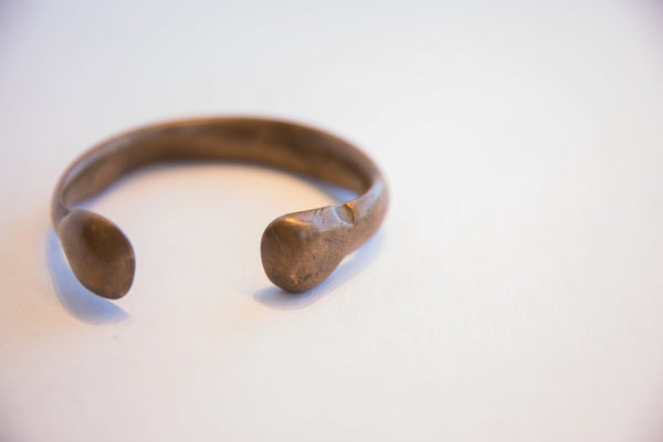 Angled view of the antique cuff bracelet's hand-worked, rounded terminal.