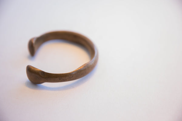 Profile view of the antique African bracelet's handmade C-shape and aged patina.