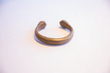 Side profile of an antique African cuff bracelet, detailing its open shape and flared ends.