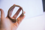 The solid, curved form of an antique African cuff bracelet held in hand.