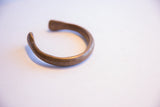 Profile of an antique African snake cuff bracelet showing its open form and warm patina.