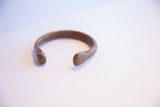 Gently curved opening of an antique African snake cuff with a time-softened patina.
