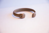 The open, stylized ends of the antique African cuff bracelet with an aged patina.