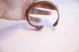 The sculpted snake head and curved open form of the antique African bracelet.