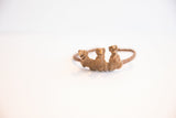 Three stylized Dogon figurines with a rustic, aged patina on a vintage cuff bracelet.