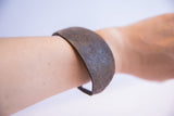 Vintage African bracelet worn on a forearm, showing its dark, textured surface and rich patina.
