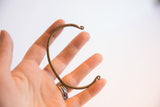 Vintage African thin cuff bracelet held to display its delicate C-shape and scale.