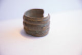 Angled view of a vintage African cuff showing its wide opening and aged surface.