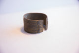 A vintage African cuff bracelet's opening, showing its etched motif and aged patina.