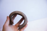 Hand holding a vintage African currency cuff to show its scale and aged patina.