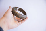 Vintage African cuff bracelet held in hand, showing scale and textured, aged patina.