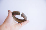 Vintage African cuff bracelet held to display its open, curved shape and scale.