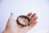 Vintage African currency cuff bracelet held in hand to demonstrate its scale.