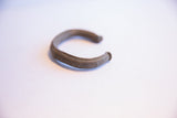 Side view of a vintage African cuff showing its curved C-shape and dark aged patina.
