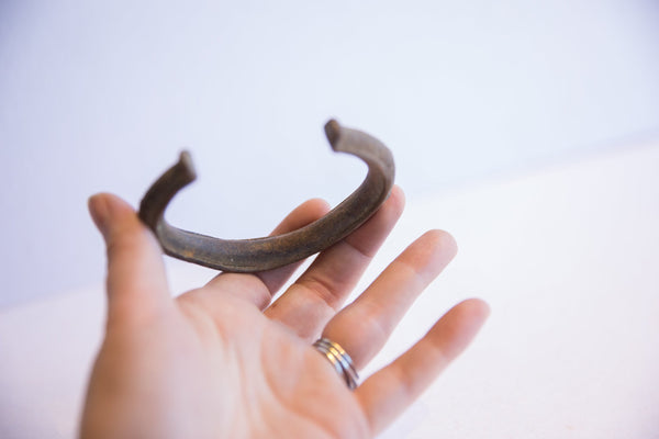 Vintage African cuff bracelet held in hand, showing its scale and dark aged patina.
