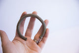 Vintage African cuff bracelet held in a palm, illustrating its size and textured finish.