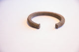 The textured metal and open C-shape of a vintage African currency bracelet.